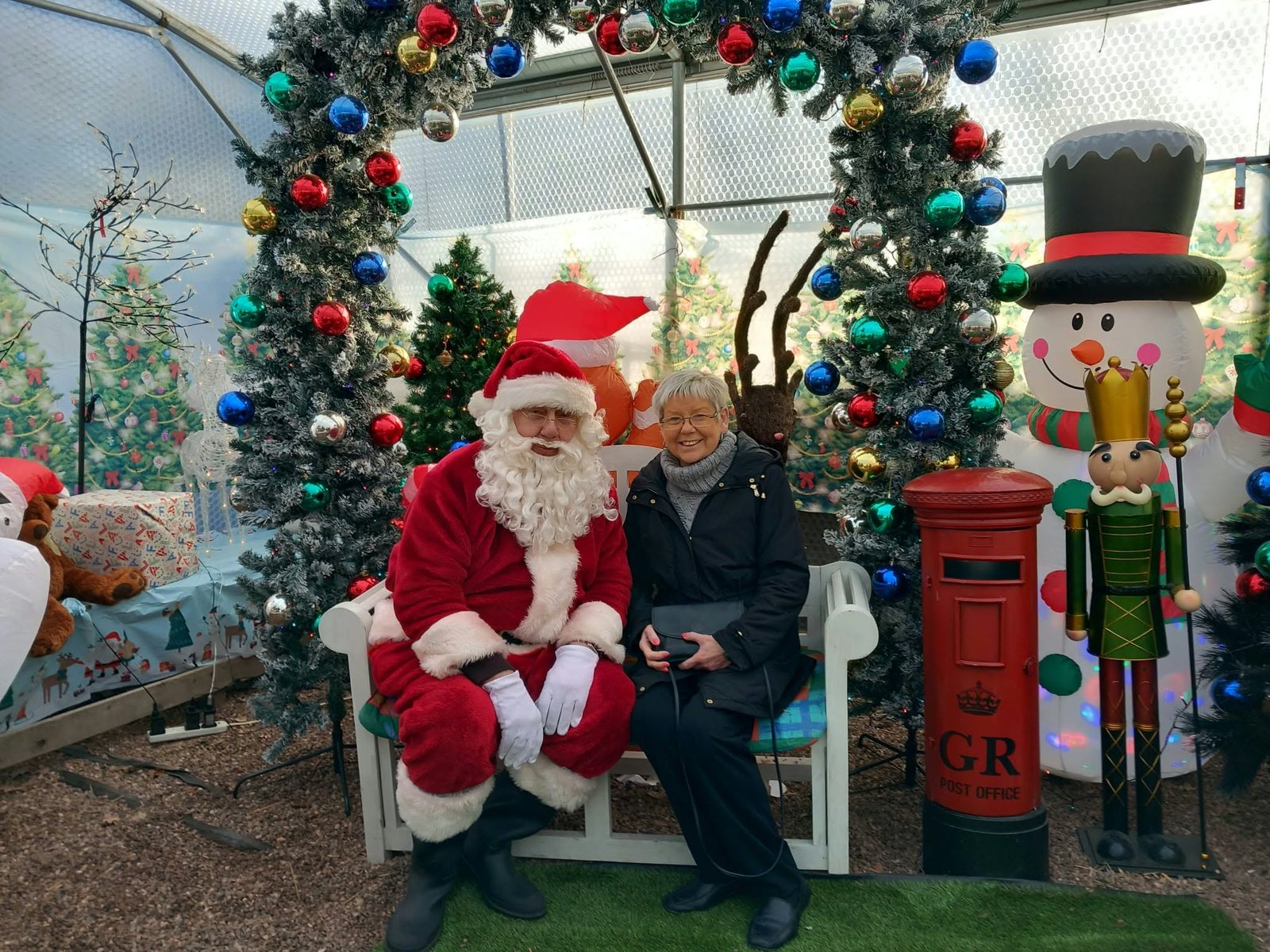 Santa seated in the grotto at Orchard Nurseries with a young visitor