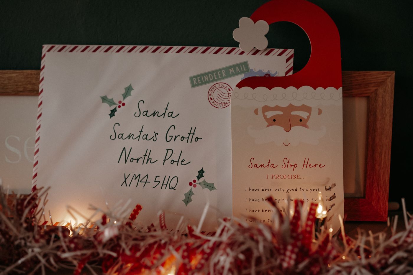 A letter to Santa surrounded by warm fairy lights and festive greenery